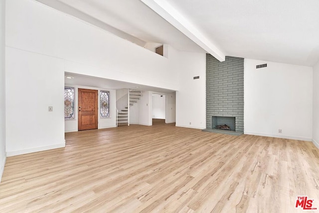 unfurnished living room with a brick fireplace, high vaulted ceiling, beam ceiling, and light hardwood / wood-style floors