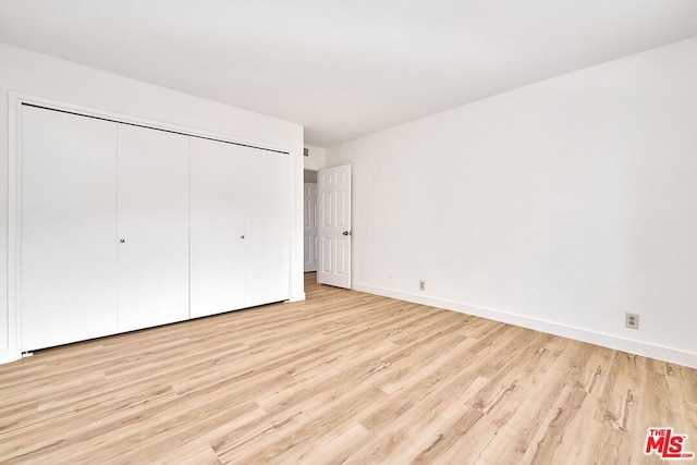 unfurnished bedroom featuring light wood-type flooring and a closet