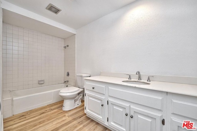 full bathroom featuring hardwood / wood-style flooring, vanity, toilet, and tiled shower / bath