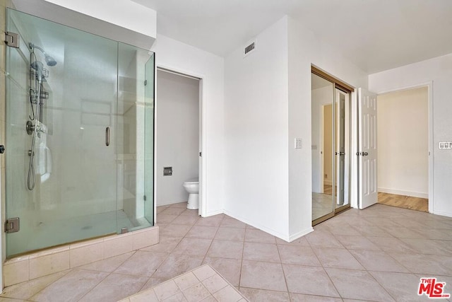 bathroom with a shower with shower door, tile patterned floors, and toilet