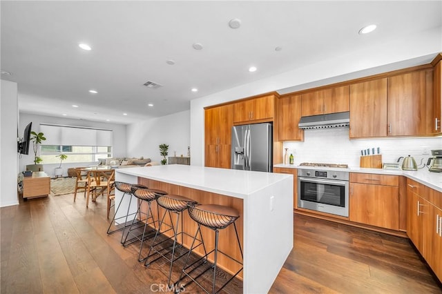 kitchen featuring a kitchen island, a breakfast bar, tasteful backsplash, dark hardwood / wood-style flooring, and stainless steel appliances