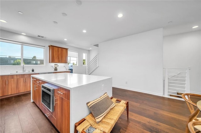 kitchen with a center island, sink, wall oven, and dark wood-type flooring