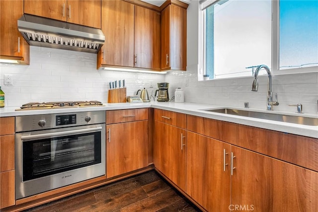 kitchen with appliances with stainless steel finishes, sink, backsplash, and dark hardwood / wood-style floors