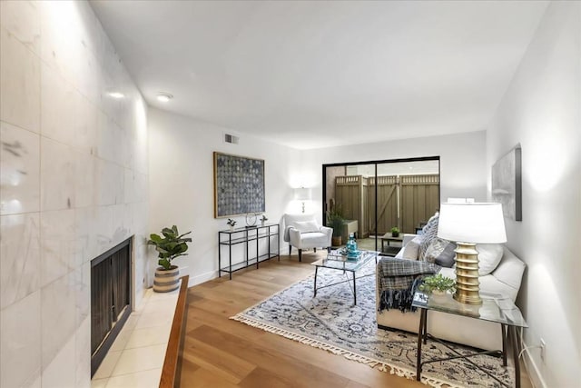 living room with a tiled fireplace and hardwood / wood-style floors