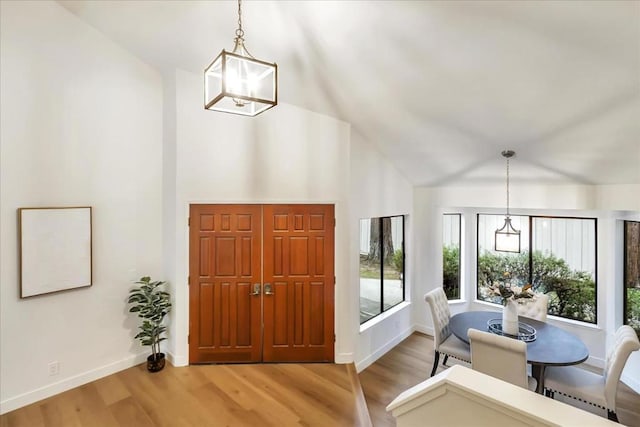 foyer entrance featuring high vaulted ceiling, a chandelier, and light hardwood / wood-style flooring