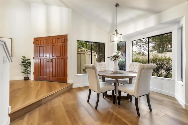 dining room featuring wood-type flooring and high vaulted ceiling