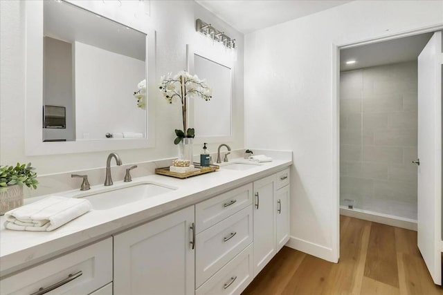 bathroom featuring tiled shower, wood-type flooring, and vanity