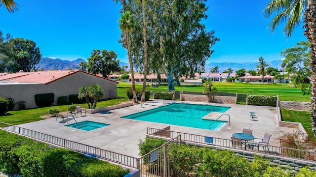 view of swimming pool with a hot tub, a patio, a mountain view, and a yard