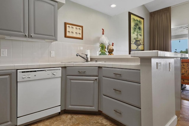 kitchen featuring sink, gray cabinetry, decorative backsplash, tile counters, and white dishwasher