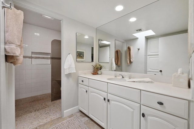 bathroom with tile patterned floors, vanity, and a tile shower