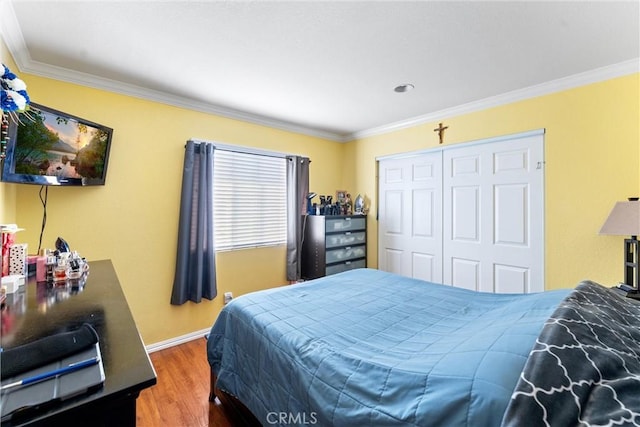 bedroom with hardwood / wood-style flooring, ornamental molding, and a closet