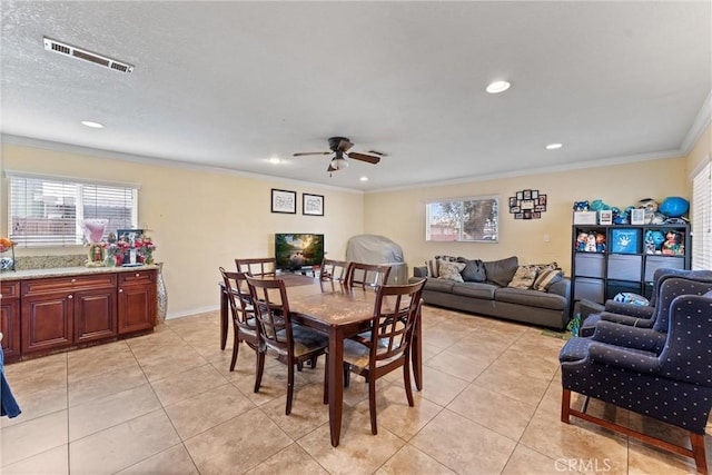 tiled dining space with crown molding, a textured ceiling, and ceiling fan