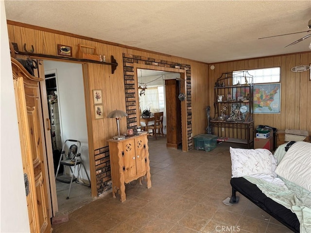 living area with ceiling fan, plenty of natural light, crown molding, and wooden walls