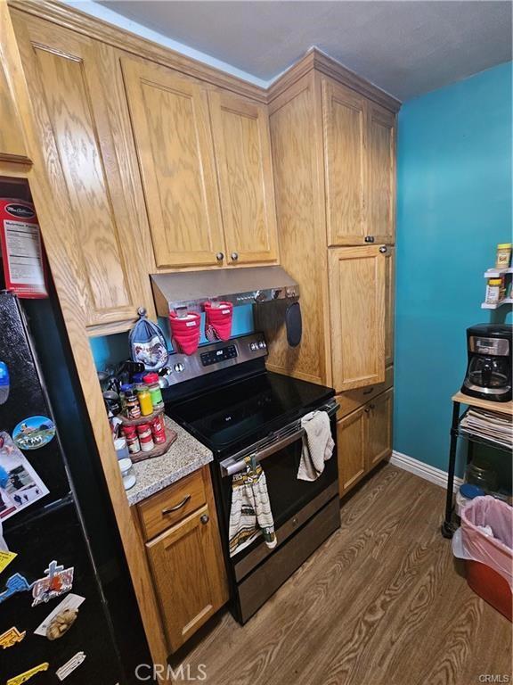 kitchen featuring black fridge, light stone countertops, electric range oven, and dark wood-type flooring