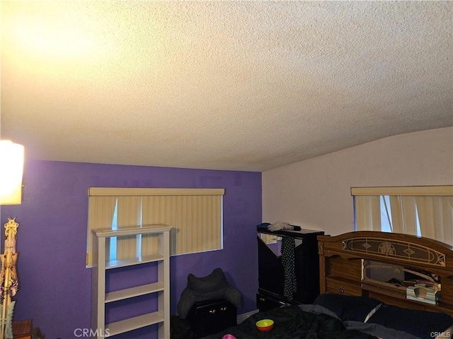 bedroom with vaulted ceiling and a textured ceiling