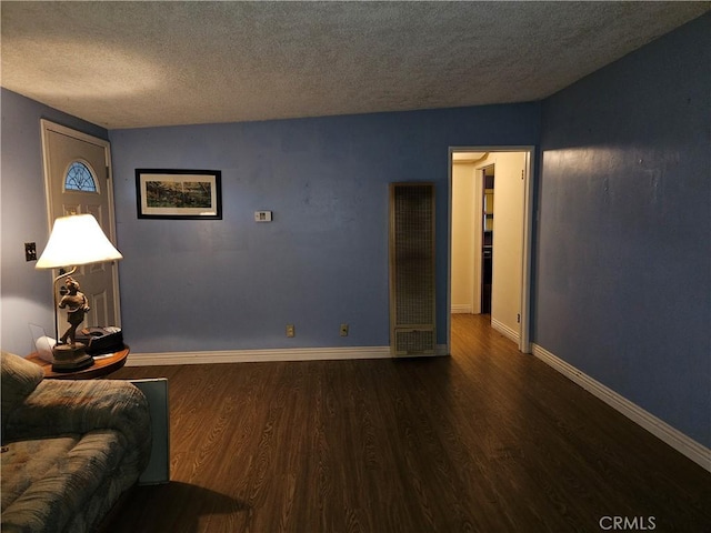 living room featuring dark wood-type flooring and a textured ceiling