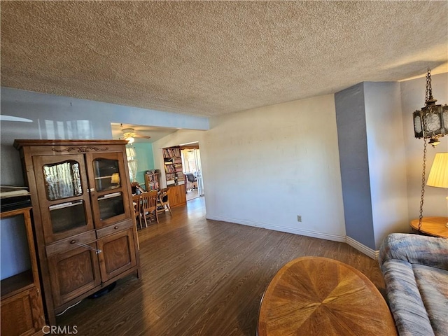 living room with ceiling fan, a textured ceiling, and dark hardwood / wood-style flooring