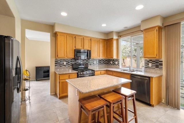 kitchen featuring decorative backsplash, a kitchen island, appliances with stainless steel finishes, a breakfast bar area, and light stone countertops