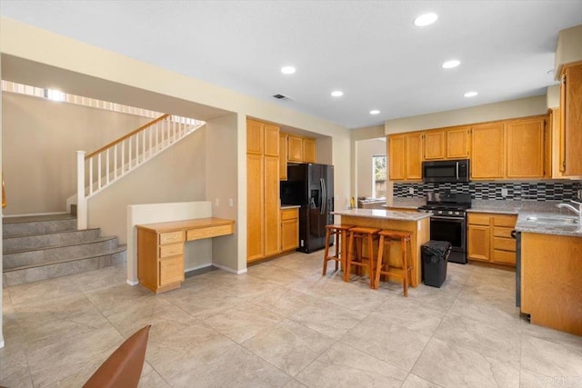 kitchen featuring a breakfast bar area, black fridge with ice dispenser, visible vents, a center island, and gas stove