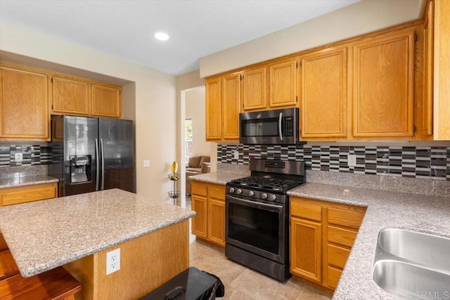 kitchen featuring appliances with stainless steel finishes, a center island, backsplash, and a kitchen bar