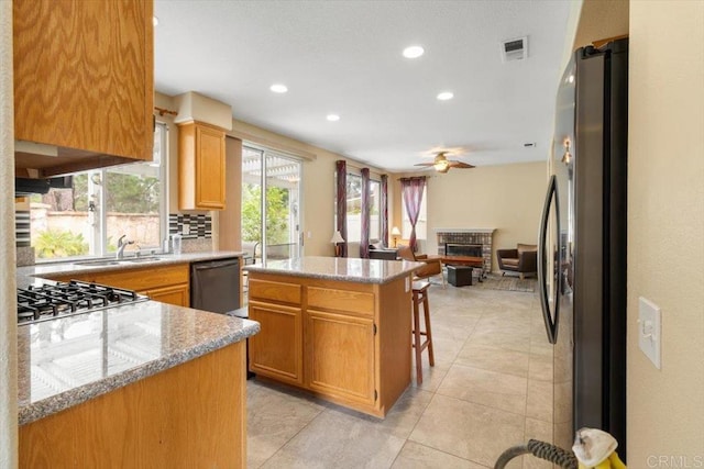 kitchen featuring a breakfast bar area, decorative backsplash, freestanding refrigerator, a kitchen island, and dishwasher