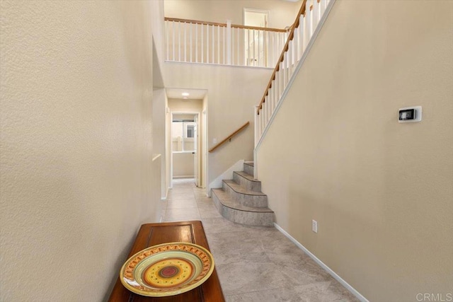 staircase with baseboards and a high ceiling