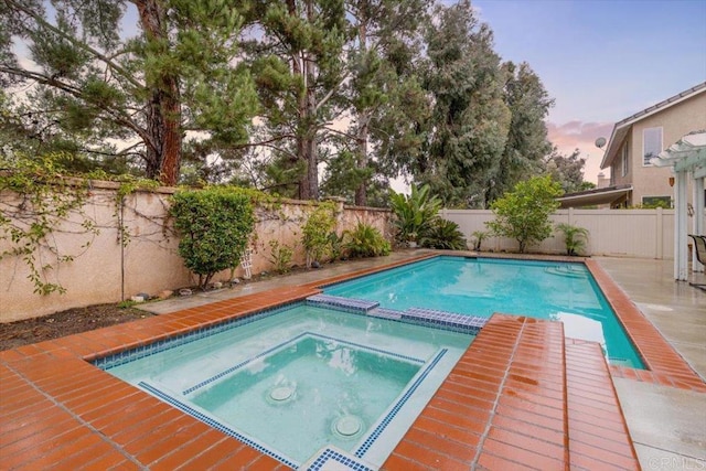 view of swimming pool with a fenced backyard and a pool with connected hot tub