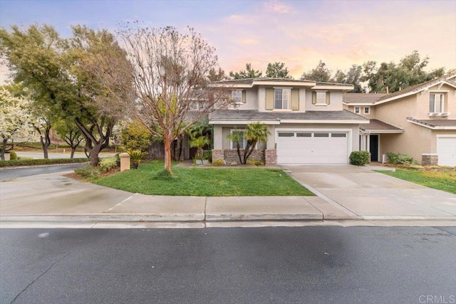 view of front of home featuring an attached garage, a tile roof, driveway, a yard, and stucco siding