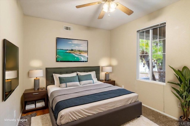 carpeted bedroom with a ceiling fan, multiple windows, visible vents, and baseboards