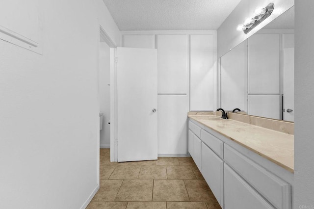 bathroom with tile patterned flooring, vanity, and a textured ceiling