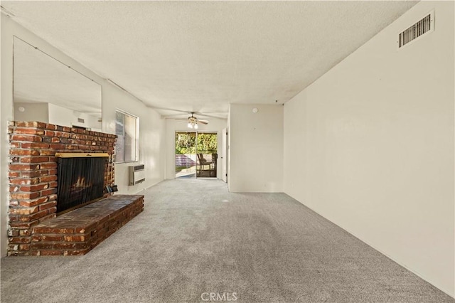 unfurnished living room featuring ceiling fan, carpet, heating unit, a textured ceiling, and a brick fireplace