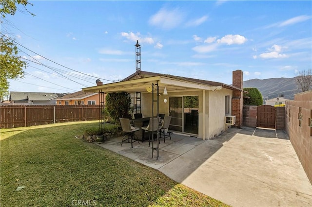 back of house with a mountain view, a yard, and a patio area