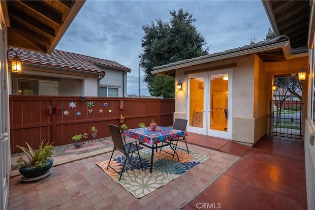 view of patio with outdoor dining space, french doors, and fence