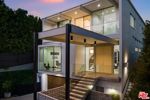 back house at dusk featuring a balcony