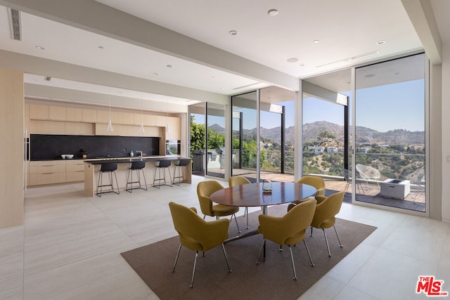 dining room featuring floor to ceiling windows, a mountain view, and light tile patterned flooring