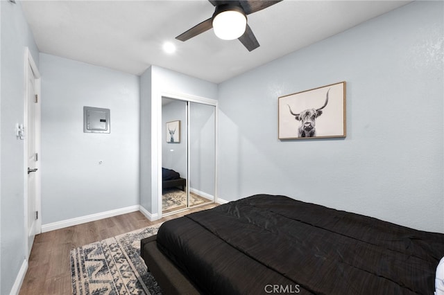 bedroom featuring wood-type flooring, electric panel, a closet, and ceiling fan