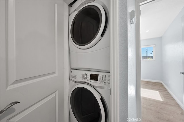 washroom featuring light hardwood / wood-style flooring and stacked washing maching and dryer