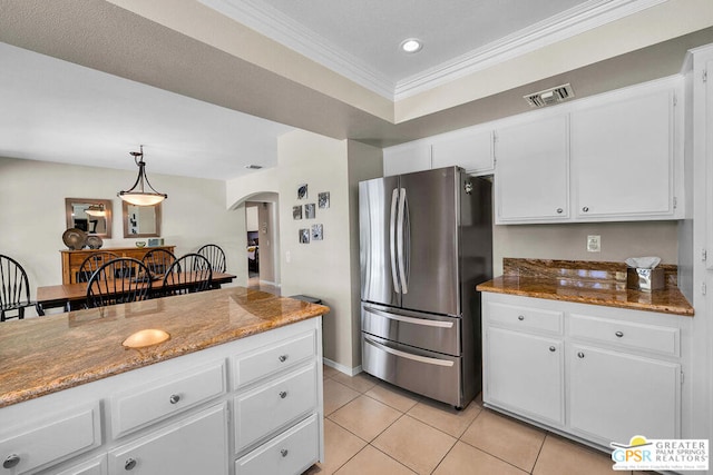 kitchen featuring white cabinetry, crown molding, light stone counters, stainless steel refrigerator, and pendant lighting