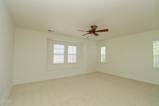 empty room with ceiling fan and light carpet