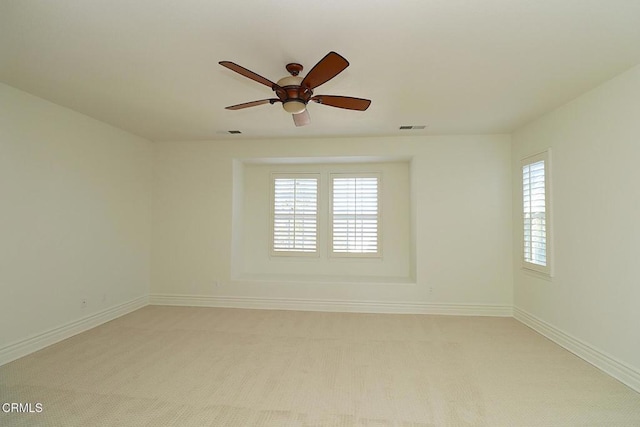 spare room featuring a wealth of natural light, light carpet, and ceiling fan