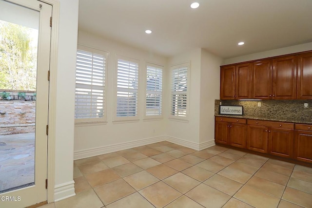 kitchen featuring dark stone countertops, light tile patterned floors, and decorative backsplash