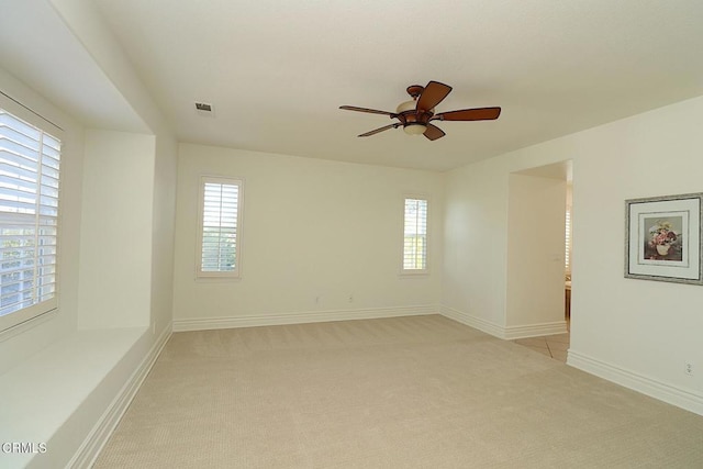 spare room featuring a wealth of natural light, light carpet, and ceiling fan