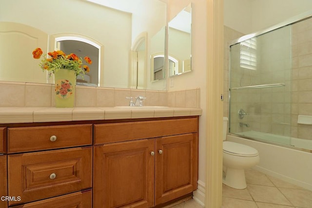 full bathroom with vanity, bath / shower combo with glass door, tile patterned floors, and toilet