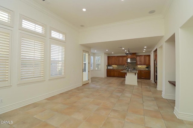 kitchen featuring light tile patterned flooring, an island with sink, backsplash, a kitchen breakfast bar, and ornamental molding