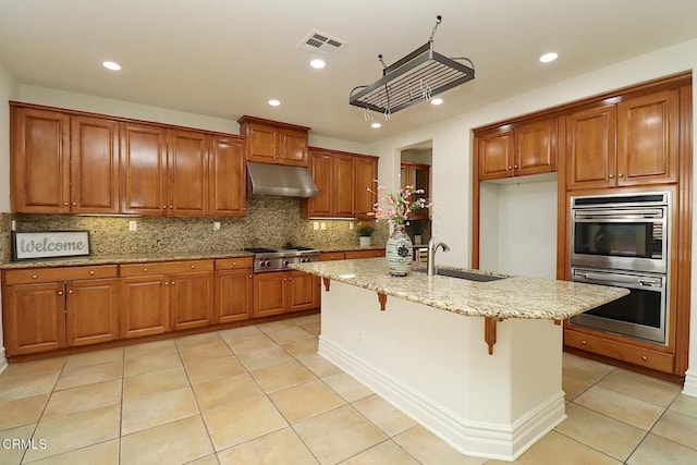 kitchen with a kitchen island with sink, sink, a breakfast bar, and appliances with stainless steel finishes