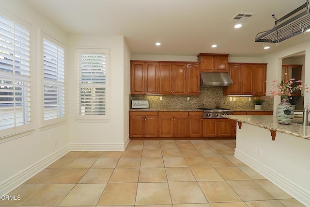 kitchen with light stone counters, stainless steel gas cooktop, decorative backsplash, and light tile patterned floors