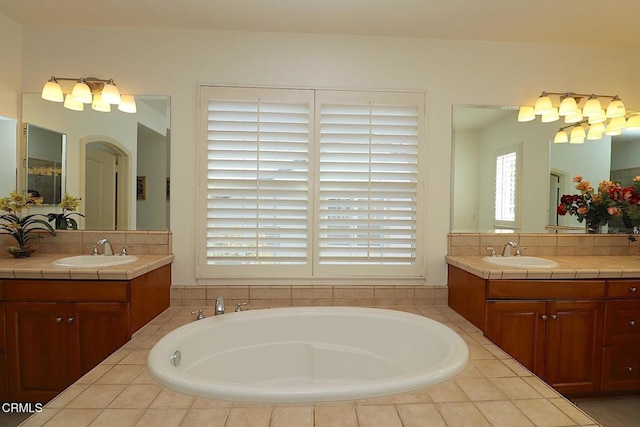 bathroom with vanity, a relaxing tiled tub, and decorative backsplash