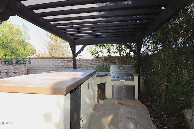 view of patio / terrace featuring exterior kitchen, a grill, and a pergola