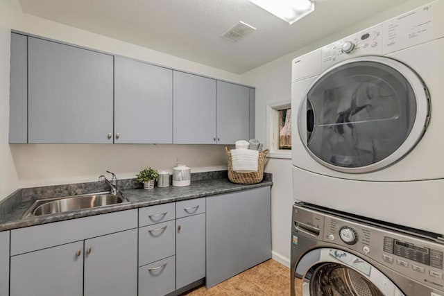 clothes washing area featuring cabinets, stacked washer and clothes dryer, and sink