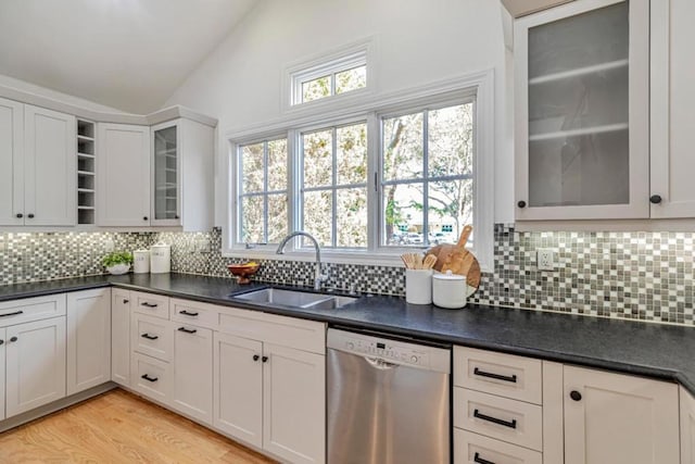 kitchen with vaulted ceiling, sink, white cabinets, stainless steel dishwasher, and light hardwood / wood-style flooring